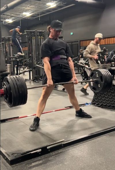 Sam locking out a sumo deadlift in the gym